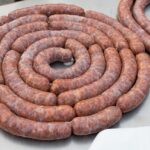 Salsiccia alla siciliana cucinata, servita con contorni tipici e decorazioni gastronomiche.