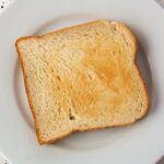 Fette biscottate su un tavolo, con un'etichetta che evidenzia ingredienti poco salutari.